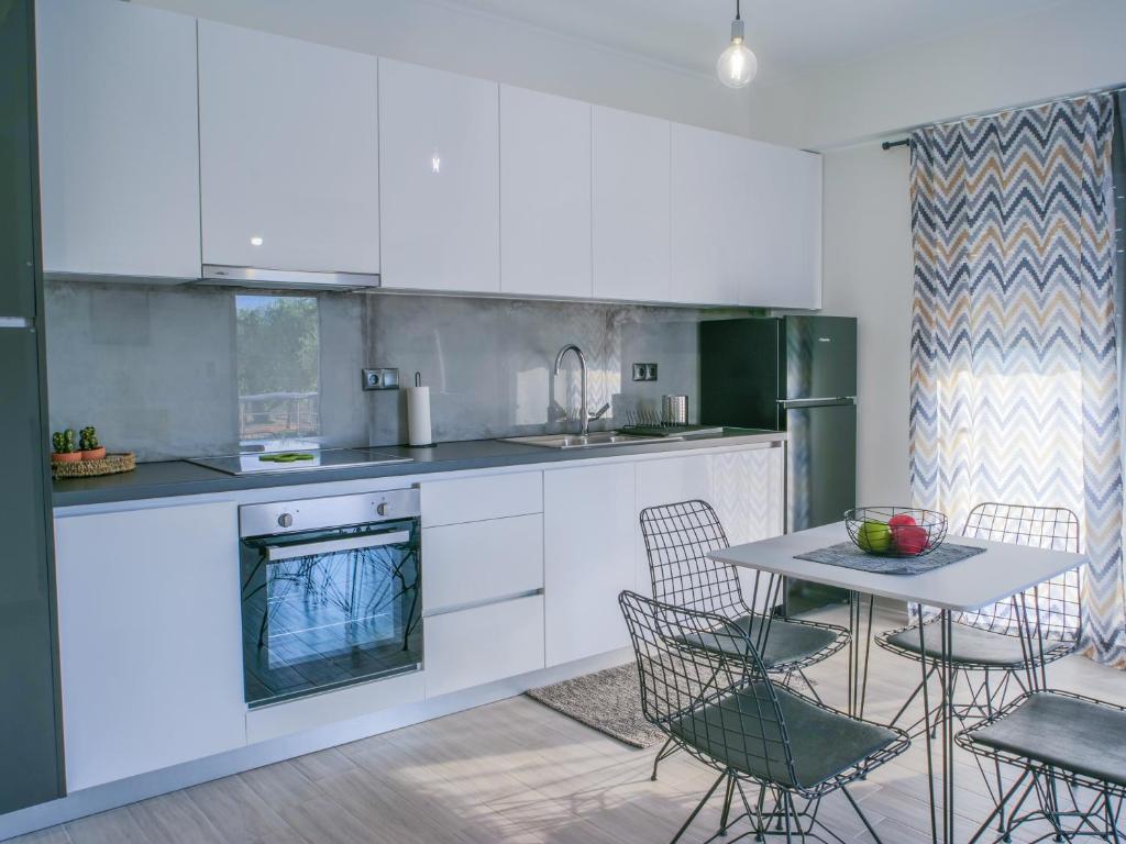 a kitchen with white cabinets and a table with chairs at ChriLenia Aparments in Kalamata