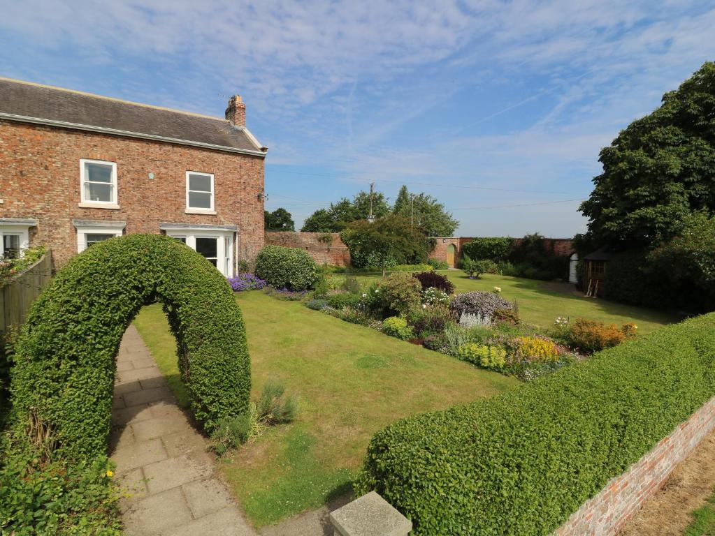 a garden with a hedge arch in front of a house at Chestnuts at Youlton Lodge in York