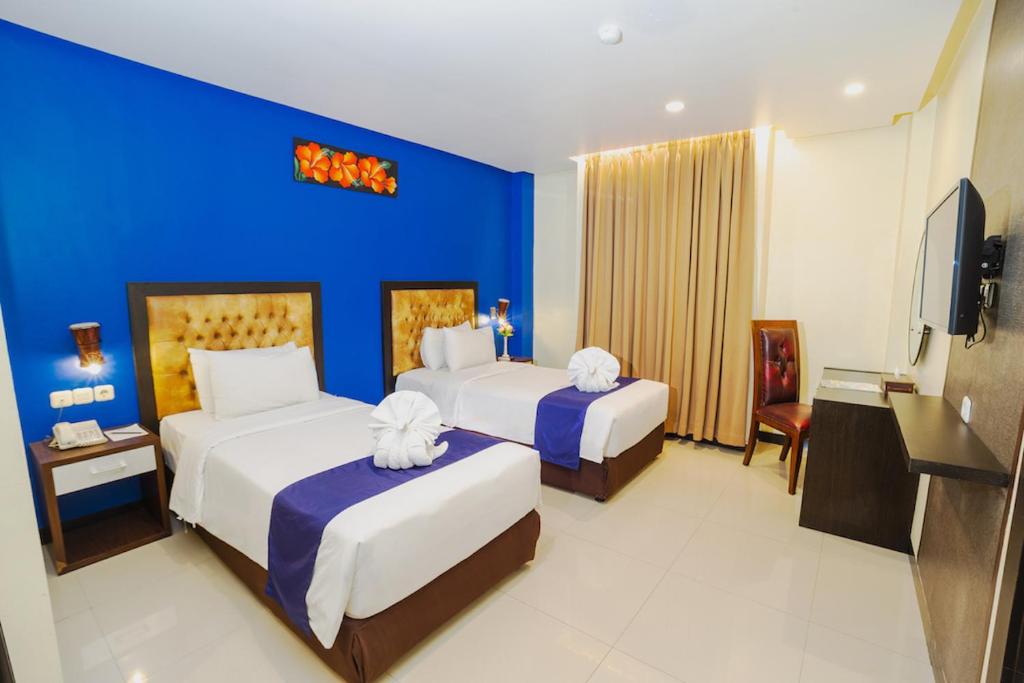 查亞普拉的住宿－Parkside Star Hotel Jayapura，酒店客房设有两张床和蓝色的墙壁。