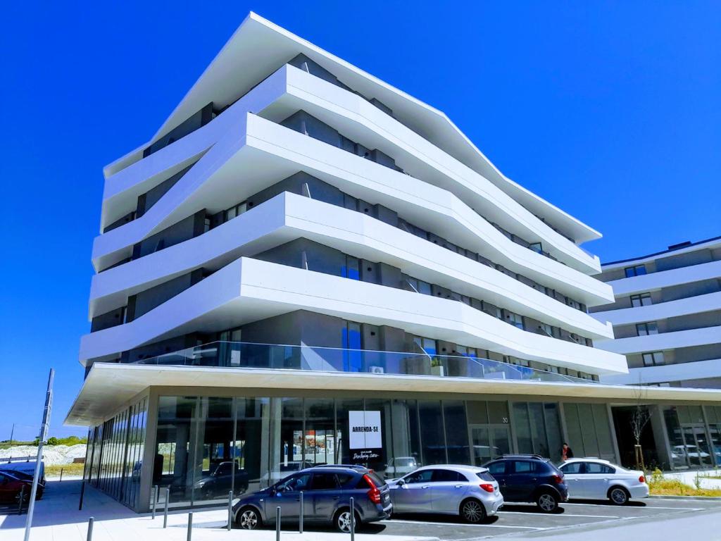 White Design Apartment في أفيرو: مبنى ابيض فيه سيارات تقف امامه