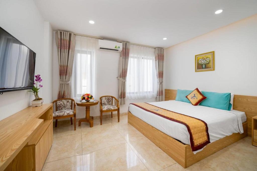 a bedroom with a bed and a table and a television at Blue-S Hotel & Apartment in Da Nang