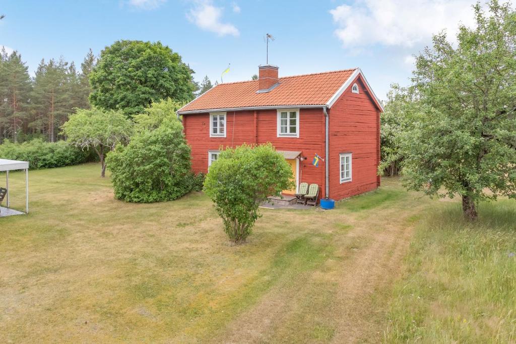 una casa roja en un patio con árboles en Cozy cottage with proximity to lake with jetty en Vimmerby