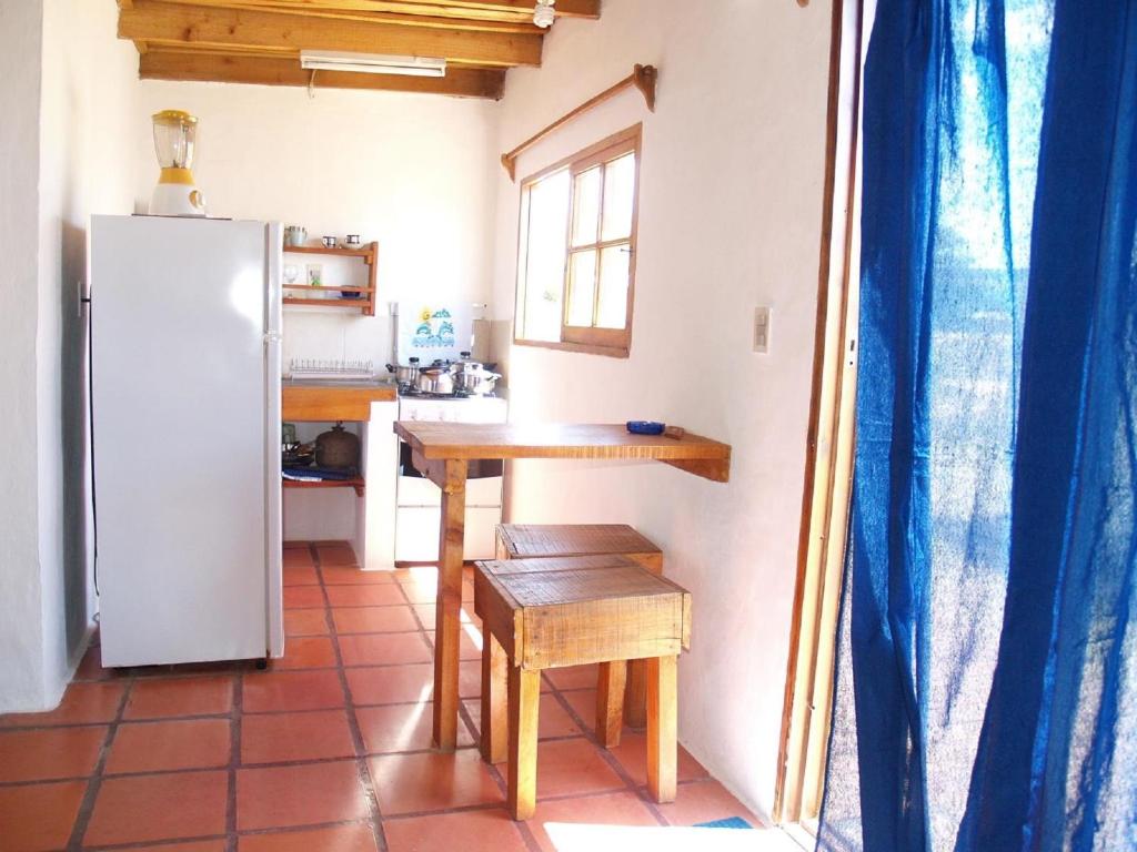 a small kitchen with a table and a refrigerator at La Joya del Diablo in Punta Del Diablo