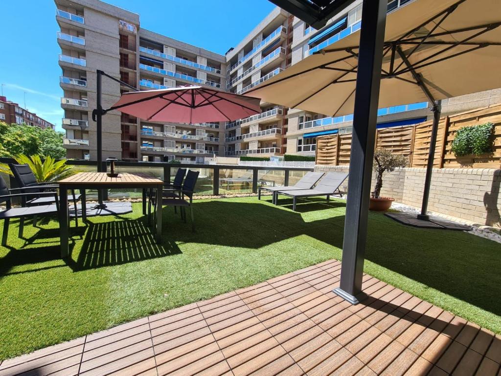 a patio with a table and chairs and an umbrella at Dos Torres Chill out in Zaragoza