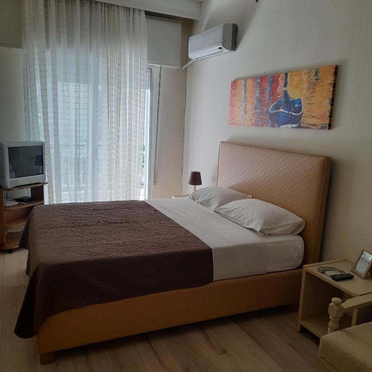 a bedroom with a bed and a television and a window at Zefi's Apartment in Nea Peramos