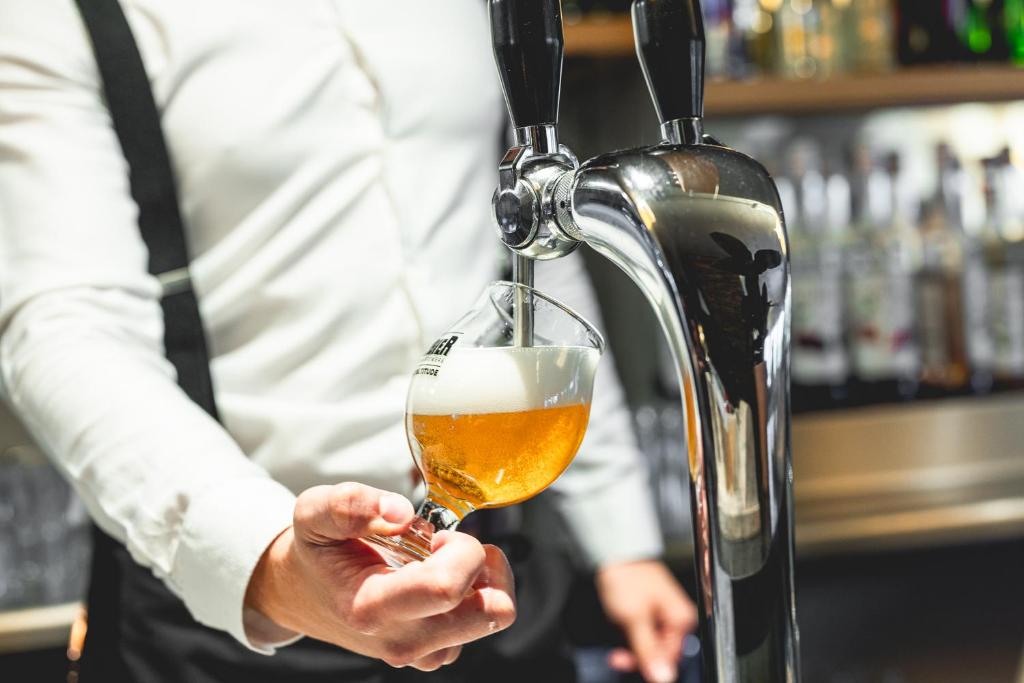 a man pouring a glass of beer in a bar at Le Grand Aigle Hotel & Spa**** in La Salle-les-Alpes