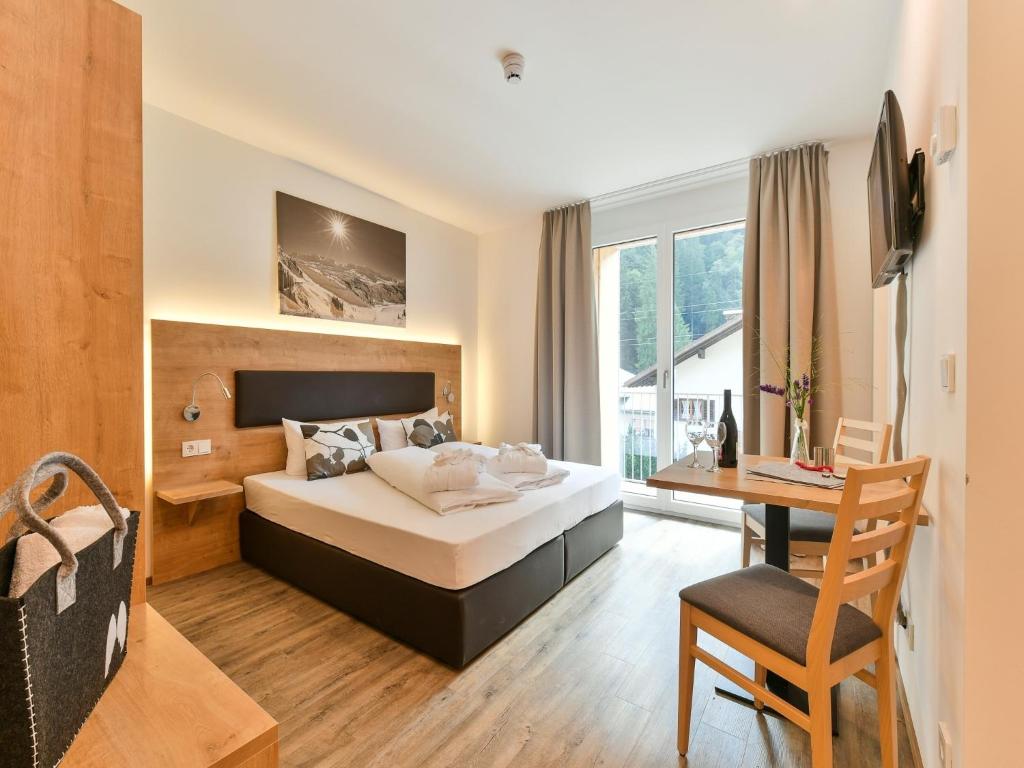 een slaapkamer met een bed, een bureau en een stoel bij Studio in der Alpine Lodge in Klösterle am Arlberg