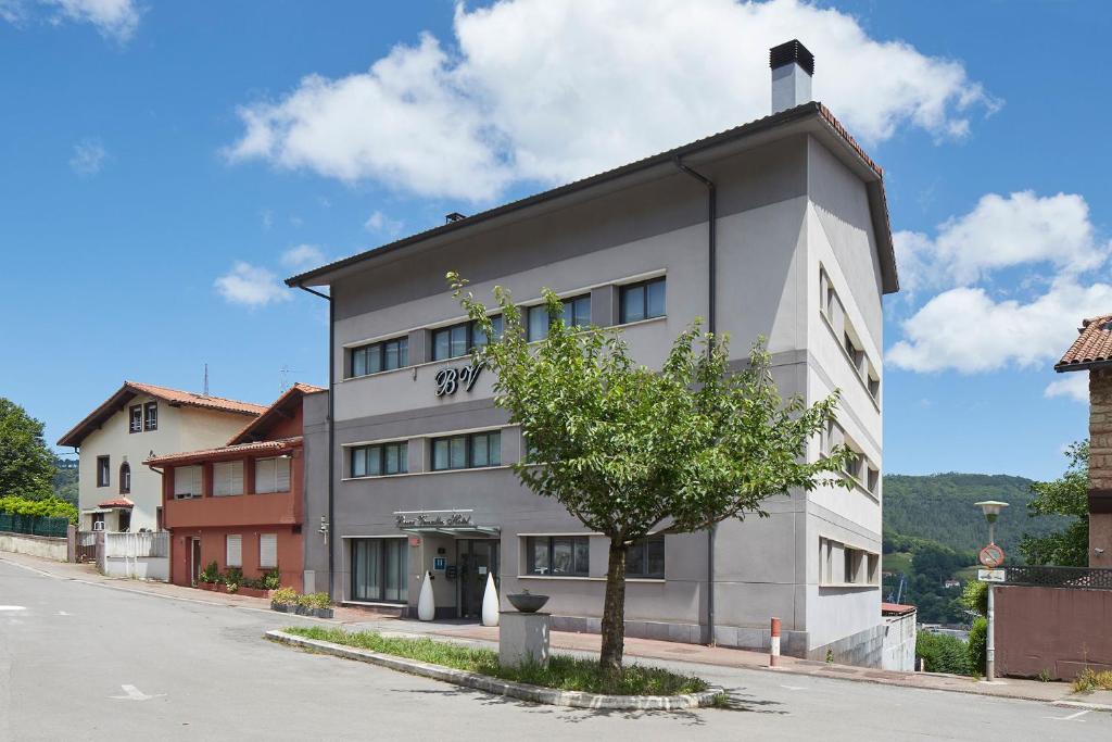 a white building with a tree in front of it at Hotel Berri Versalles in Rentería