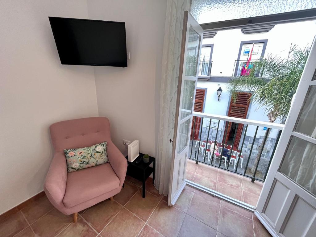 ein Wohnzimmer mit einem Stuhl und einem Flachbild-TV in der Unterkunft GATU Sabor a Cádiz in Cádiz