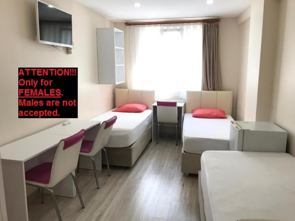 ein Zimmer mit drei Betten und einem Tisch und Stühlen in der Unterkunft !ONLY FEMALES! Bakirkoy Ladies Dormitory in Istanbul