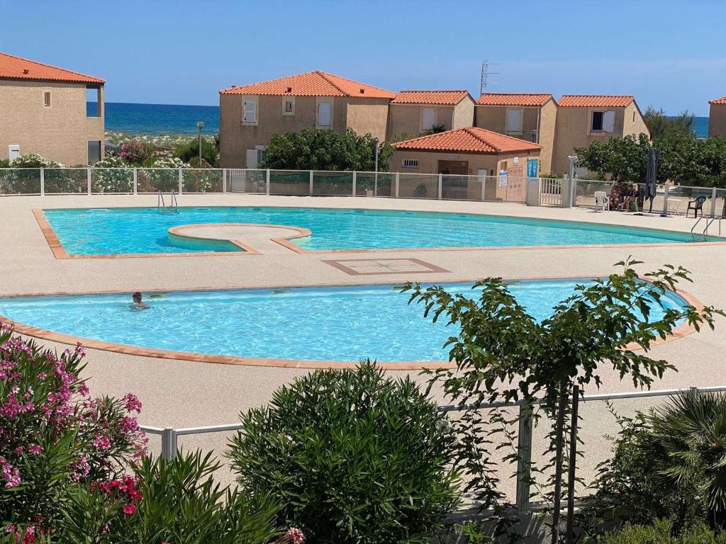 une grande piscine devant certains bâtiments dans l'établissement Villa T3 en bord de mer avec piscine, 6 personnes - Le Barcarès - FR-1-81-494, au Barcarès
