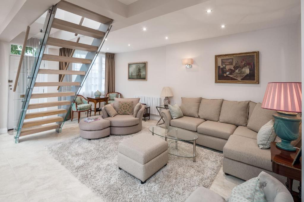 a living room with a couch and a staircase at JOIVY Fabulous 4BR house with terrace at the heart of Notting Hill in London