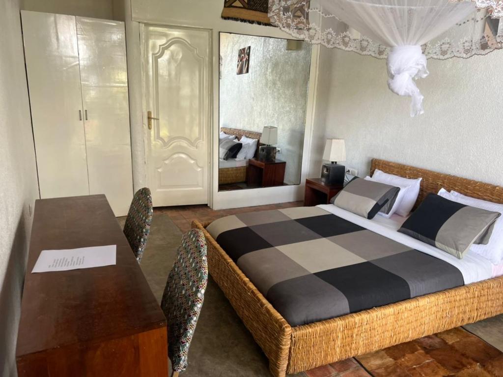 1 dormitorio con 1 cama y 1 mesa con sillas en Palm garden Resort en Gisenyi