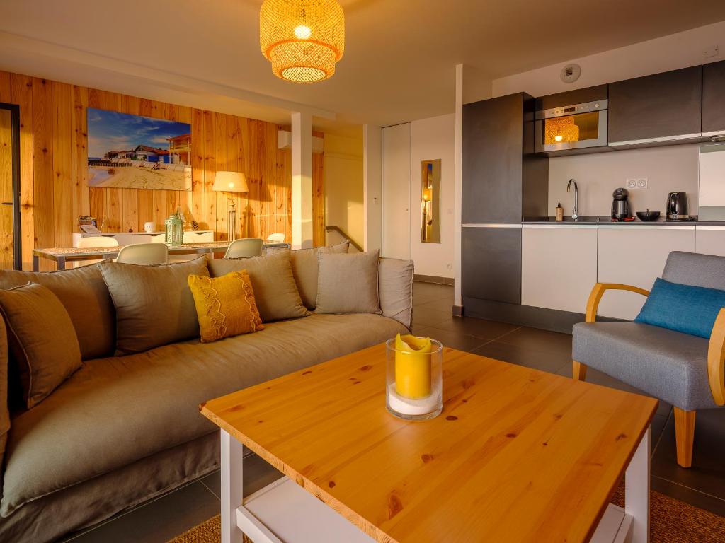 a living room with a couch and a wooden table at Résidence Les Suites Du Ferret in Cap-Ferret