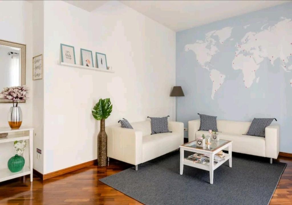 a living room with a white couch and a world map on the wall at Romely House St Peter Apartment in Rome