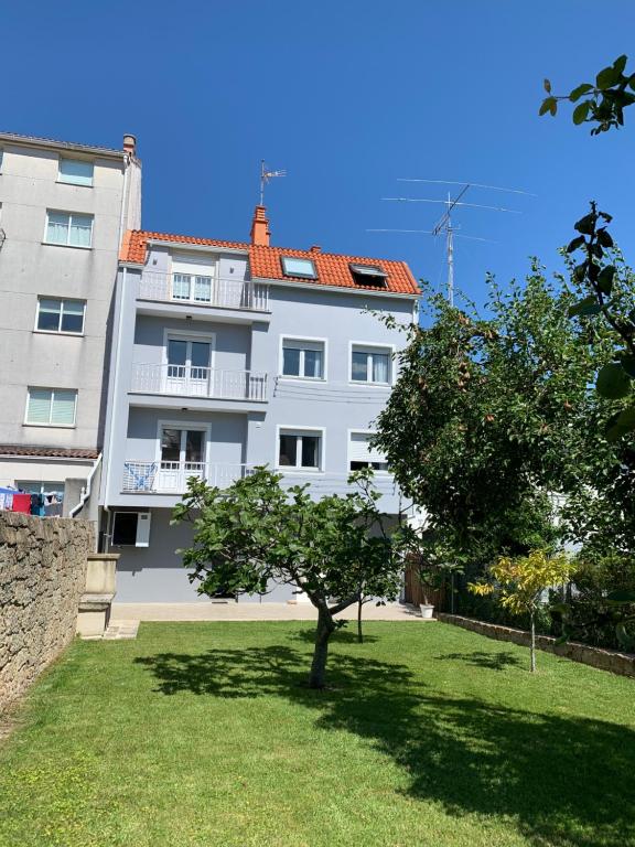 un gran edificio blanco con un árbol en el patio en VUT Pedra do Con, en Portosín