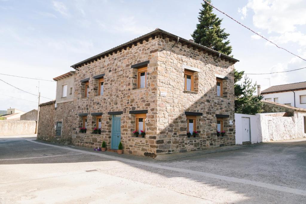 a stone building with a blue door on a street at Casa rural el gato encantado in Matalebreras