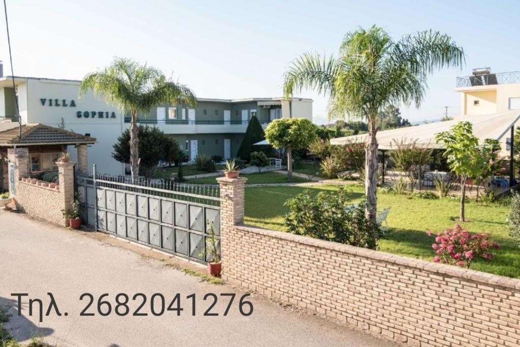 a brick fence in front of a yard with palm trees at Villa Sophia in Mytikas