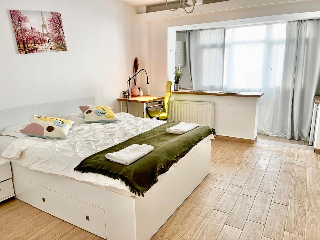 a bedroom with a white bed and a kitchen at Victoriei studio in Bucharest