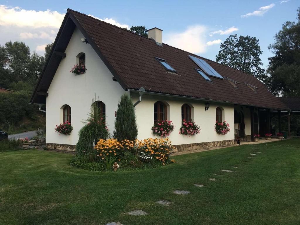 a white house with flowers in front of it at Farma Malenice in Malenitz