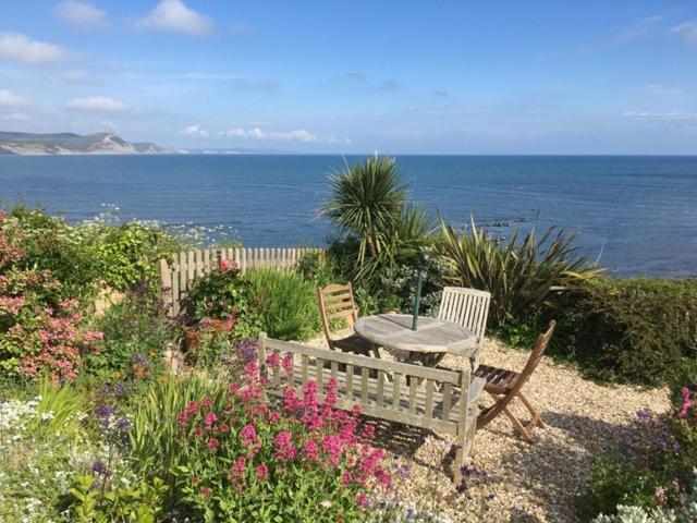 a table and chairs sitting next to the ocean at 4 East Cliff in Lyme Regis