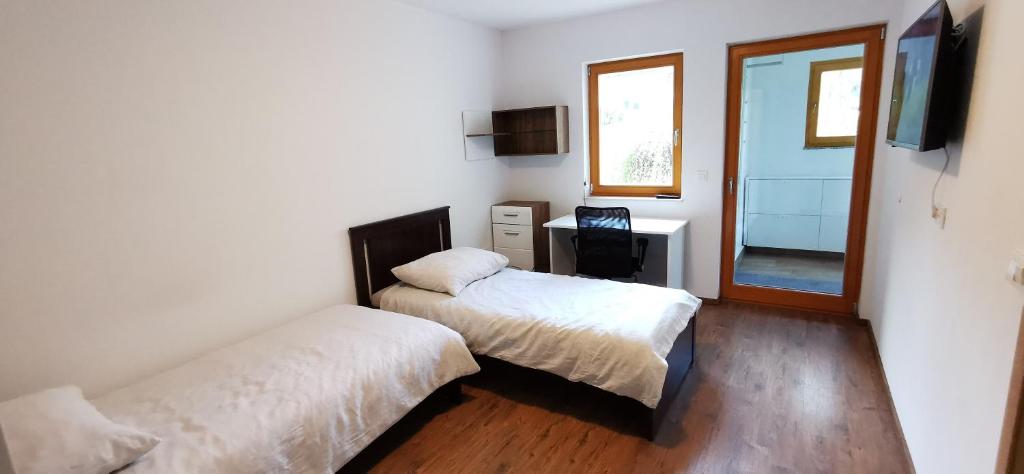 a bedroom with two beds and a desk and a television at Apartments Domovoj in Medvode