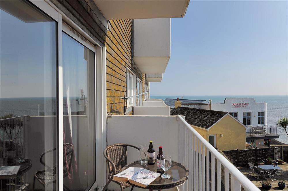 a balcony with a table with wine bottles on it at 4 Bay View Court in Lyme Regis