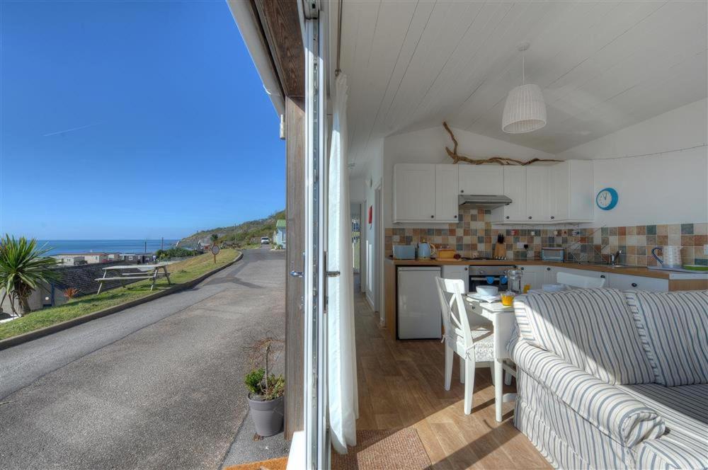 a living room and kitchen with a view of the ocean at The Beach Hut in Lyme Regis