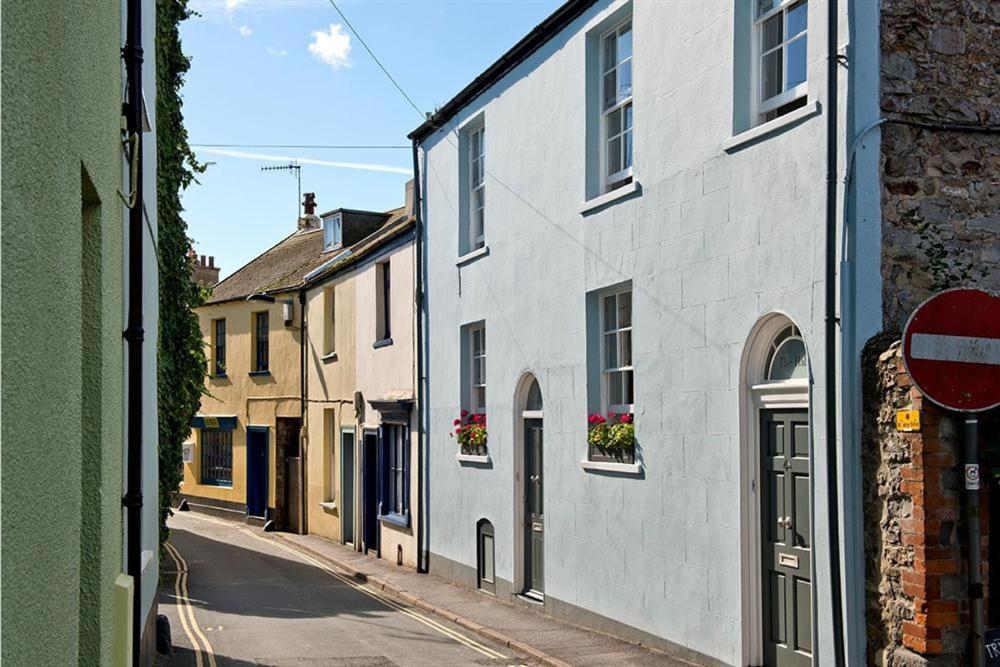 une rue étroite avec des bâtiments blancs et un panneau de rue dans l'établissement The Arched House, à Lyme Regis