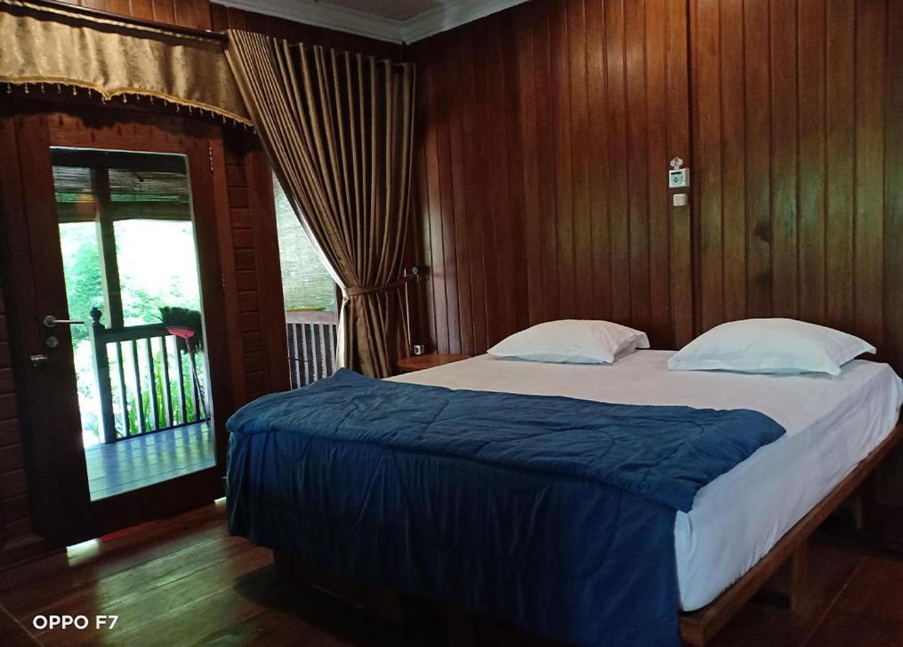 Schlafzimmer mit einem großen Bett und Holzwänden in der Unterkunft Rumah Mertua Pulau Merah in Pasanggaran