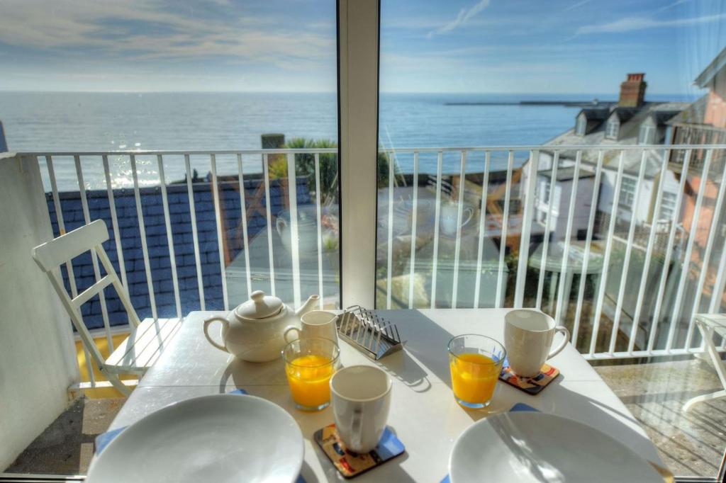 a table with two glasses of orange juice on a balcony at 6 Bay View Court in Lyme Regis