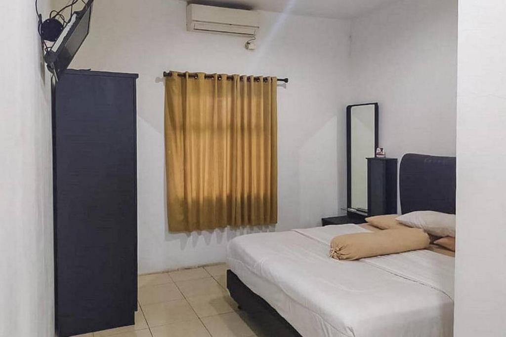 una camera con due letti, uno specchio e una finestra di Graha HT Sumantri Mitra RedDoorz a Tasikmalaya