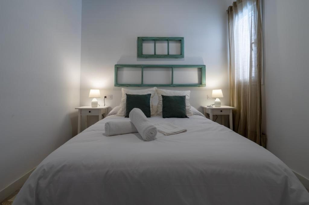 Un dormitorio con una gran cama blanca con dos lámparas. en El Mirador de El Puerto, en El Puerto de Santa María