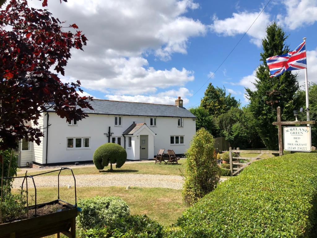 una casa blanca con una bandera delante de ella en Acreland Green, en Pleshey