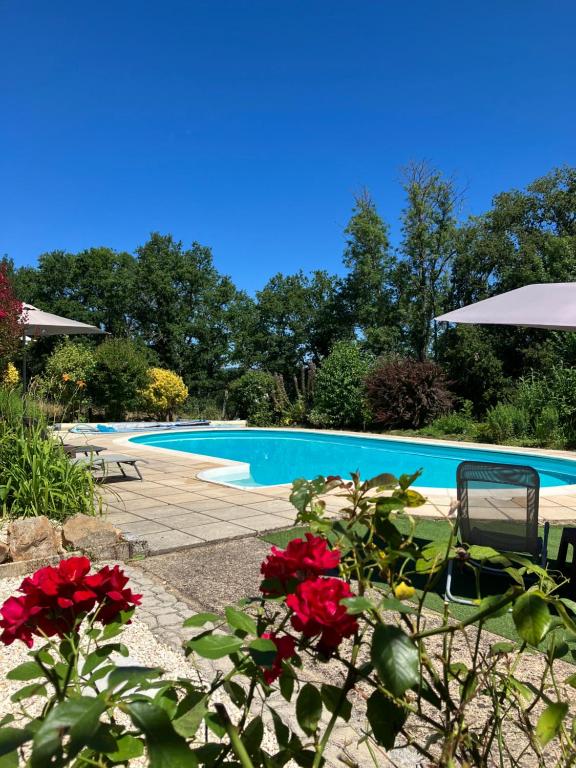 a swimming pool with red flowers in front of it at Le Petit Appartement `a Cariad La Rebeuse in Corgnac-sur-lʼIsle