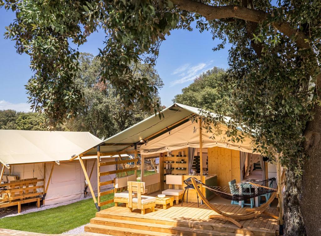 una casa con un porche y un árbol en Maistra Camping Amarin Glamping en Rovinj