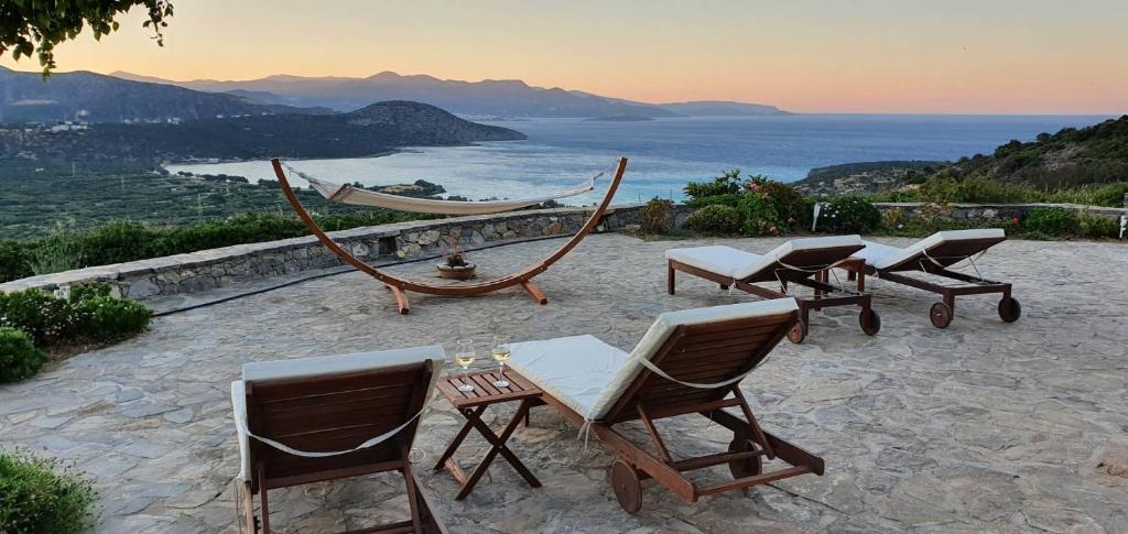- un ensemble de chaises et de hamacs sur une terrasse donnant sur l'océan dans l'établissement Marina Villas, à Istron