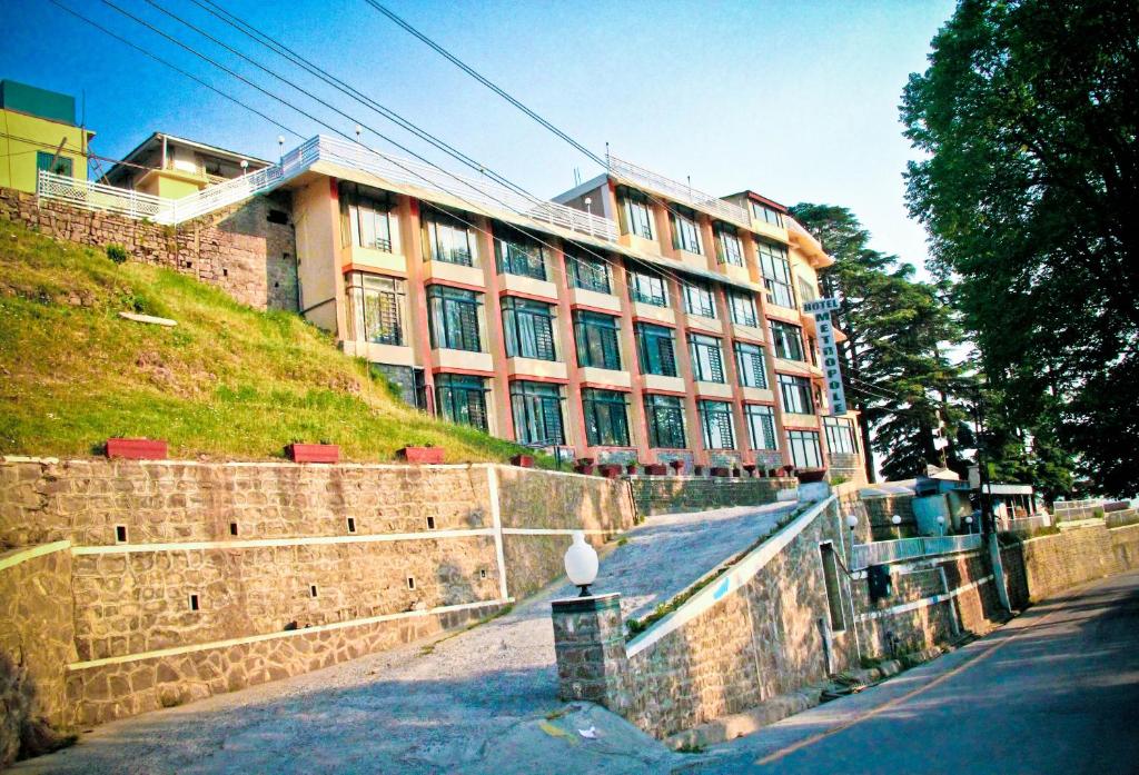 a building on a hill next to a stone wall at Metropole Hotel in Murree