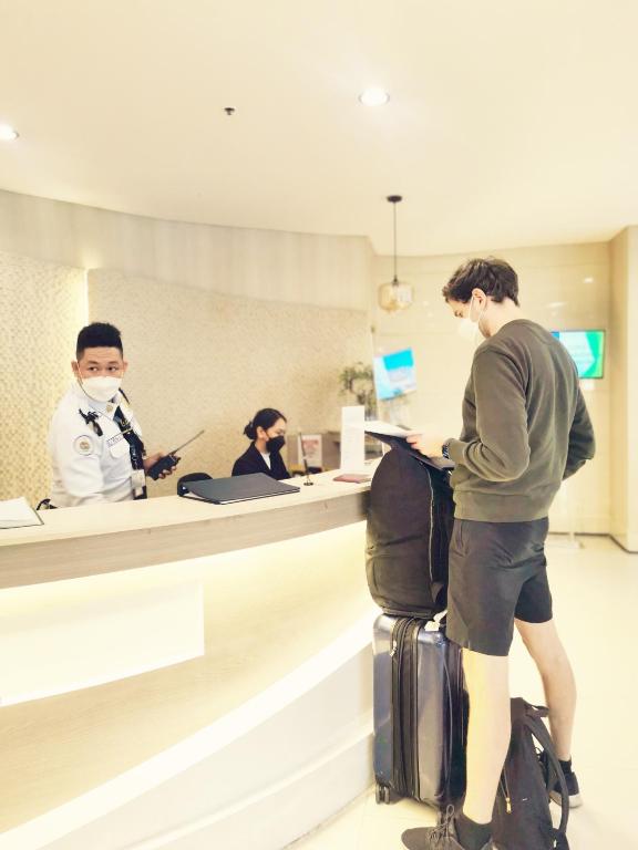 a man standing at a counter in an airport with luggage at Liam's Pad at grace residences in Manila