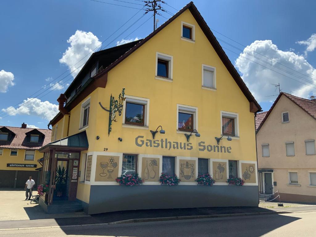 un bâtiment jaune avec un panneau sur son côté dans l'établissement Gasthaus Sonne, à Hohenstadt