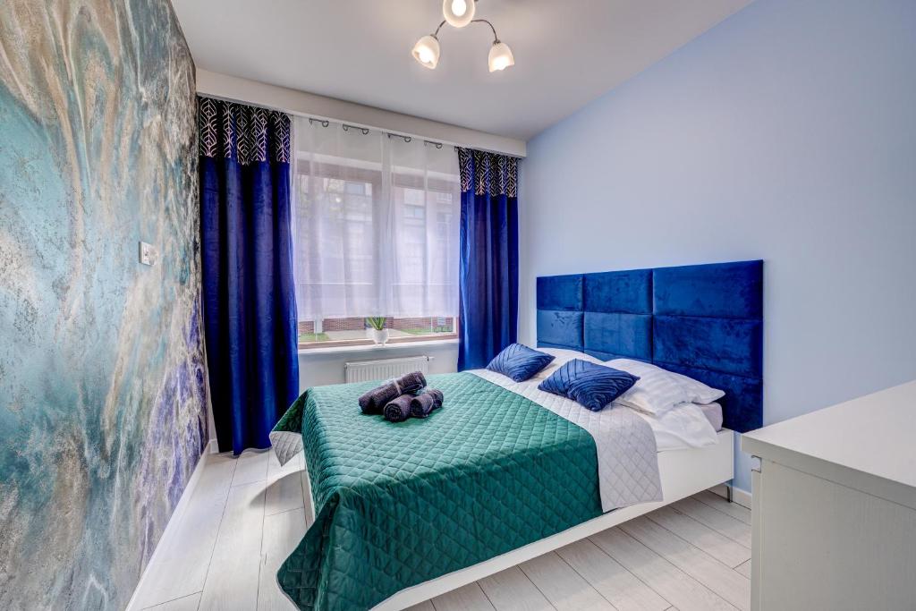Schlafzimmer mit einem Bett mit blauen Wänden und blauen Vorhängen in der Unterkunft Apartamenty Silver 4 in Stettin