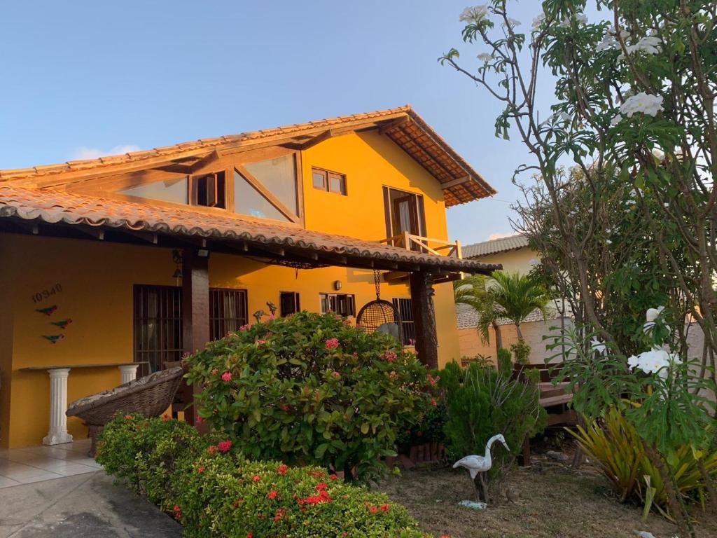 una casa amarilla con un pájaro delante de ella en Excelente casa na Praia do Coqueiro com 4 suítes a 100m da praia, en Coqueiro