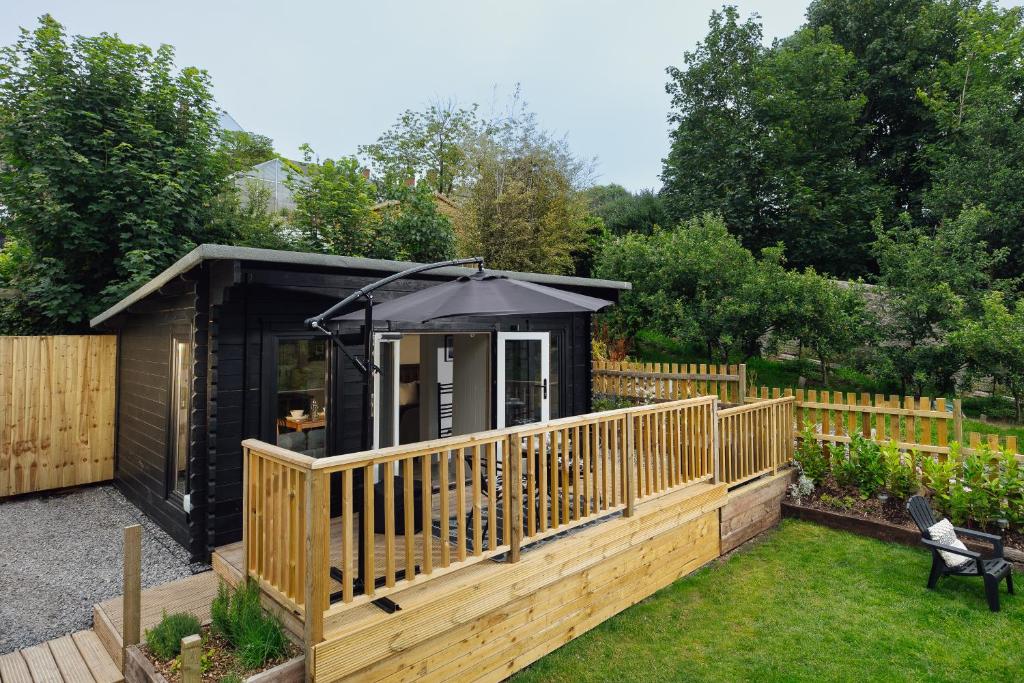 a small cabin with an umbrella on a deck at Caban Du Bach Pembroke With Private Garden in Pembrokeshire