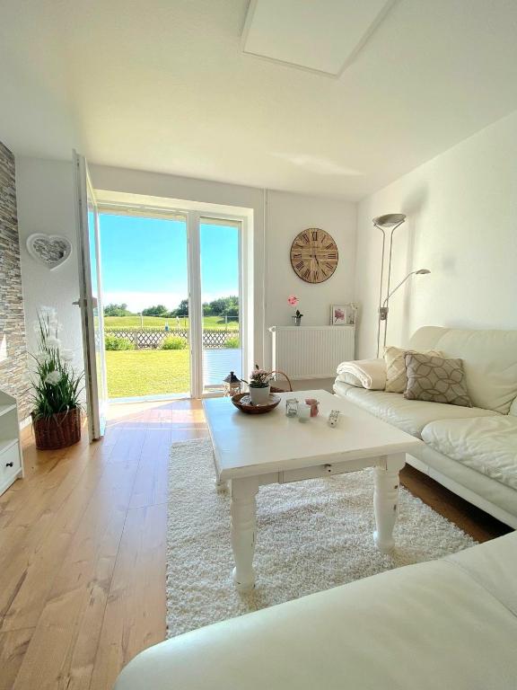 ein Wohnzimmer mit einem weißen Sofa und einem Tisch in der Unterkunft Buhr's Sonnenstern in Stolk