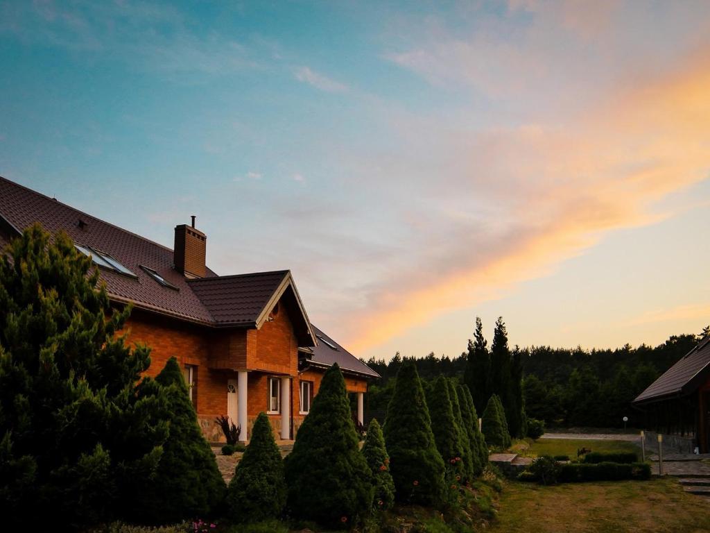 a house with trees and a rainbow in the sky at Malinowy Dworek - Spokojny wypoczynek nad morzem in Ciekocino