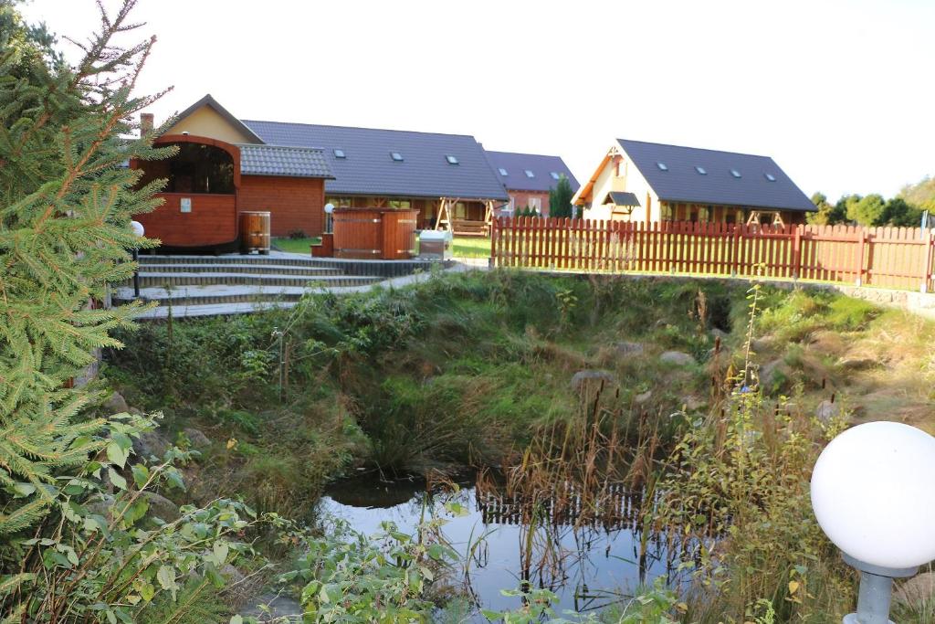 a house with a pond in front of it at Malinowy Dworek - Spokojny wypoczynek nad morzem in Ciekocino