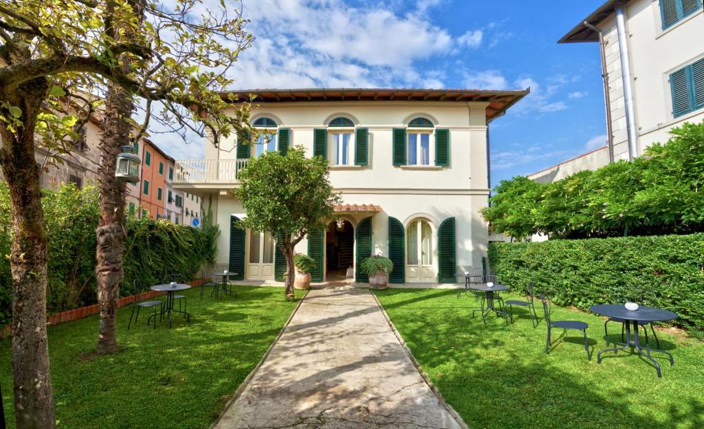 ein Haus mit einem Garten mit Tischen und Stühlen in der Unterkunft Il Piccolo Verde in Terranuova Bracciolini