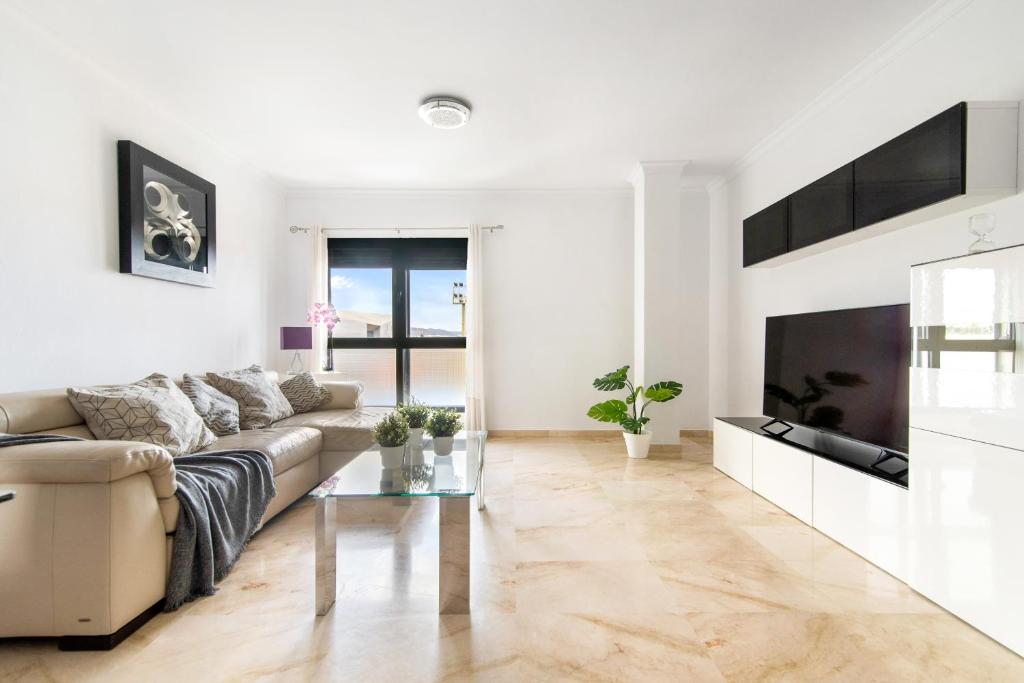 Home2Book Fantastic Design Apartment Las Palmas في لاس بالماس دي غران كاناريا: غرفة معيشة بيضاء مع أريكة وطاولة