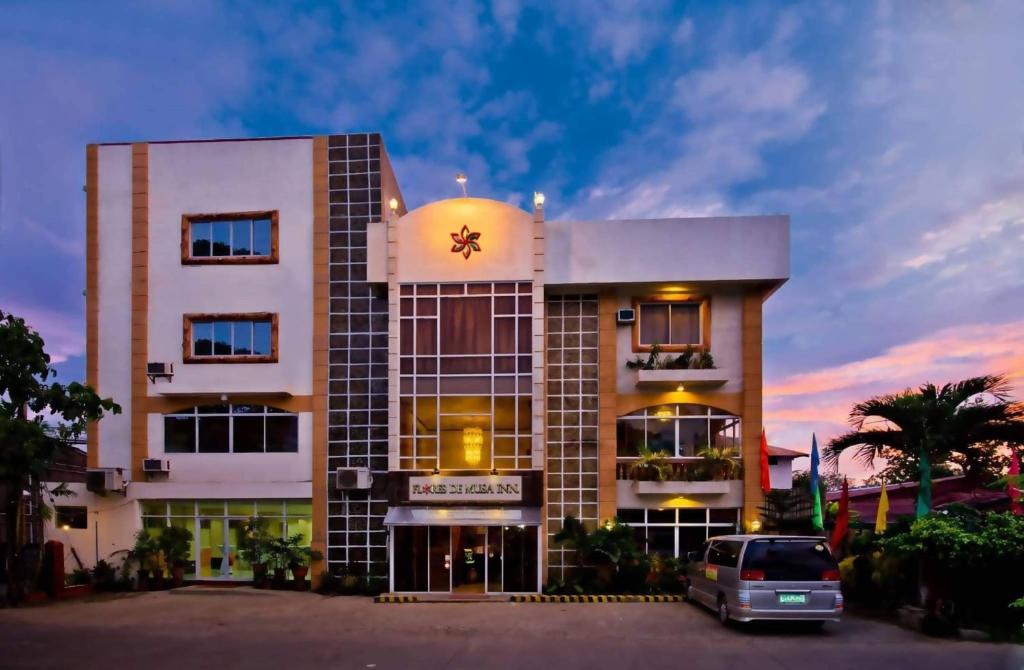 budynek z samochodem zaparkowanym przed nim w obiekcie OYO 880 Flores De Musa Inn w mieście Puerto Princesa
