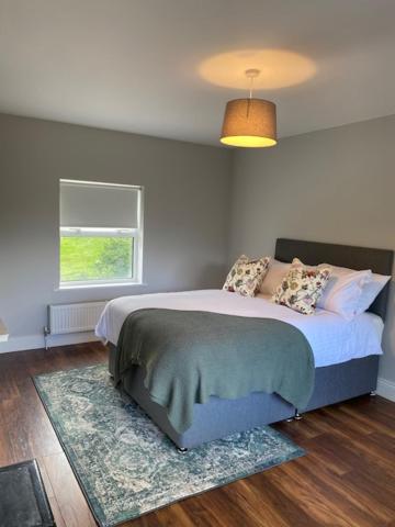 1 dormitorio con 1 cama con alfombra y ventana en Redhills Mohill, en Rivers Town